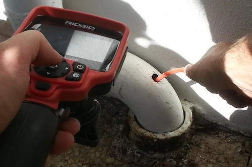 Plombier qui effectue une recherche de fuite avec une caméra endoscopique.